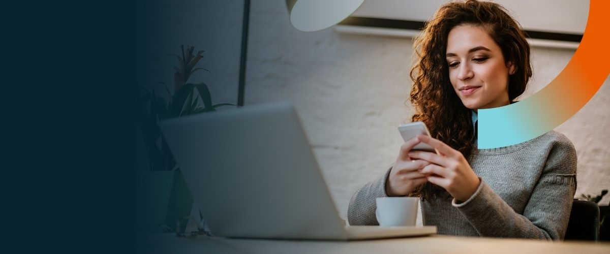 Smiling woman with glasses and backpack holds a notebook, sitting on steps. Another person reads in the background.